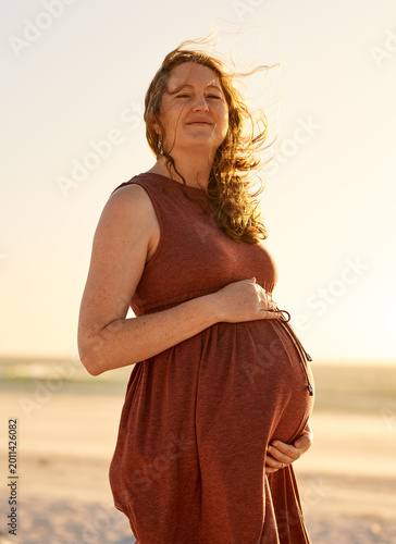 Foto Pregnant Woman Standing on Beach at Sunset Maternity Portrait, Expectant Mother