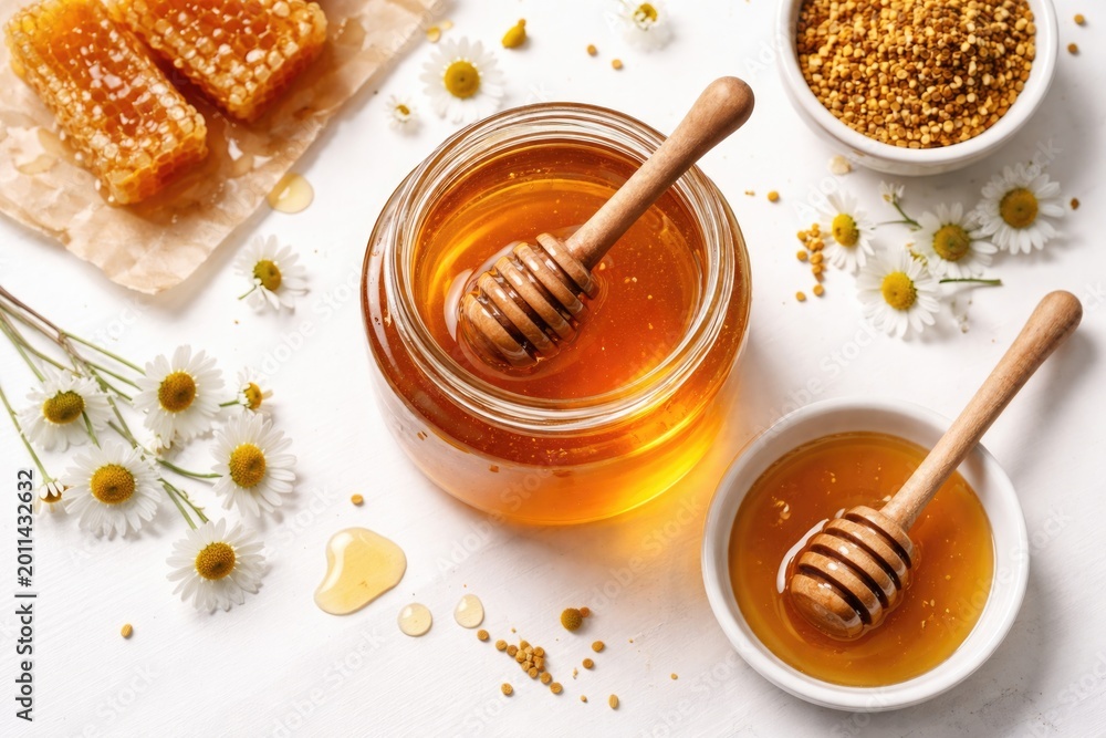 Fototapeta premium Fresh honey setup featuring wooden dipper on a white surface from top
