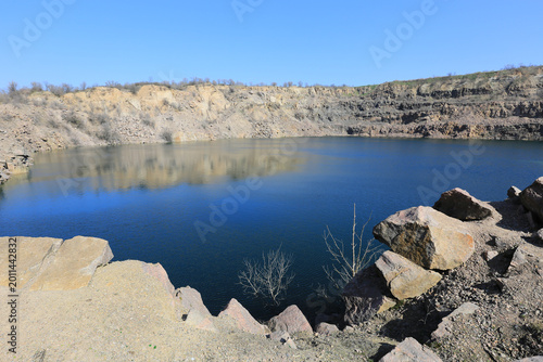 Photos Vast quarry lake with steep rocky cliffs under a clear blue sky