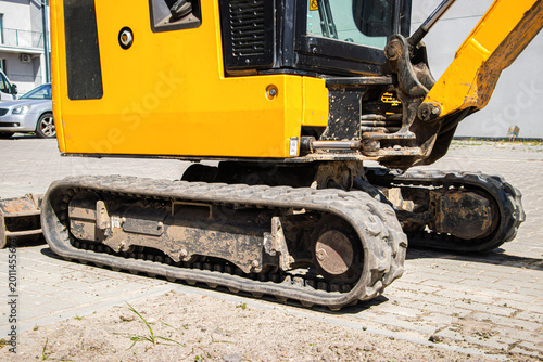 фотографія Yellow excavator with rubber tracks parked on a construction site, showing detai