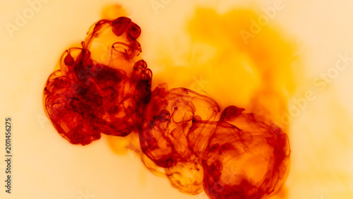 Red ink spreading through light liquid with soft organic forms and glowing warm tones