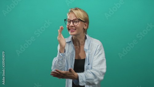 Konstfotografi Woman touching mouth and chest with hands while smiling against a teal studio backdrop; friendly joy