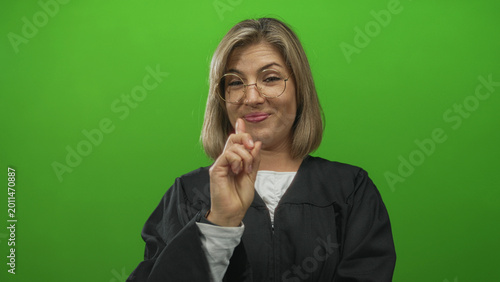 Foto Woman judge in black robe points finger to her chest in green studio set with raised eyebrow and firm expression; denial authority assertion