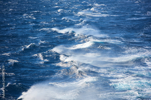 Canvas Print White sea spray and breaking waves on the deep blue surface of the Aegean Sea, S