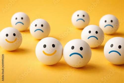 Yellow backdrop with ping pong balls showing joy and sadness icons for customer review concept