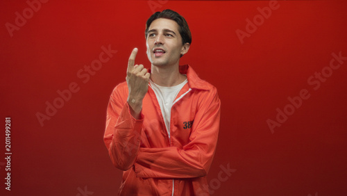 Bild auf Leinwand Man in orange prison jumpsuit with hand on chin, touching face and crossed arms in studio; contemplation regret