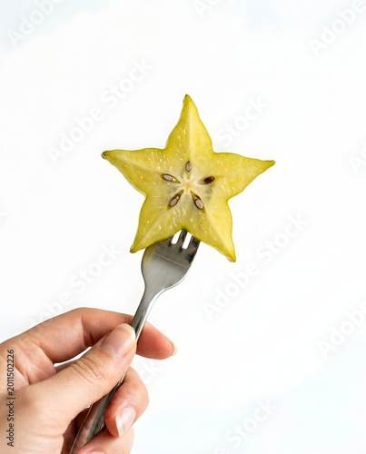 Star fruit slice impaled on a fork against a plain white background