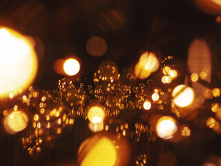 Warm glowing fairy lights and glass ornaments with golden bokeh reflections creating festive abstract holiday background