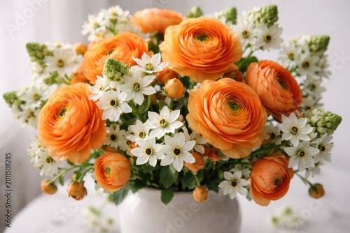 Artistic bouquet of orange ranunculus mixed with star shaped ornithogalum flowers on white base