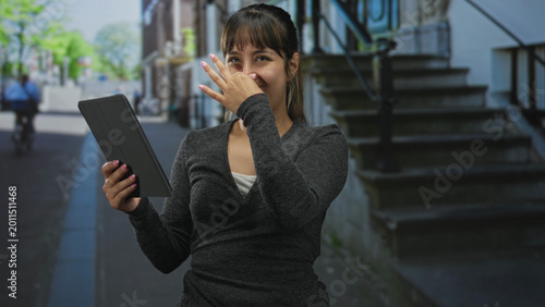 Fotografía Woman holding tablet pinches nose on a street stoop by steps, grimacing at a strong unpleasant smell; disgust odor reaction