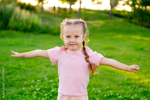 Tablou pe pânză a child runs around happily in the summer on a green lawn, spreading her arms li