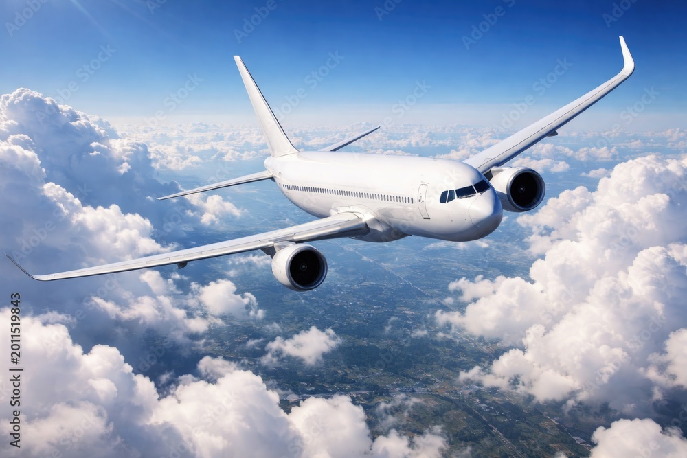 Obraz premium White plane turning left with wings angled over a sunny blue sky and billowy clouds