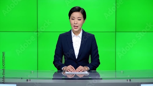 Female news anchor in formal attire presenting in front of green screen