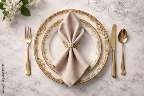 Overhead shot of elegant folded napkin on decorative china plate laid on marble table backdrop with copy space