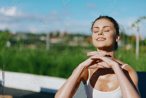 Fotografie Cheerful woman outdoors, eyes closed, basking in sunshine, relaxed posture, warm