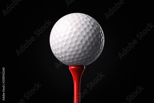 Close-range image of a white golf ball with visible texture positioned on a radiant red tee with a uniform black backdrop for sports promotional use