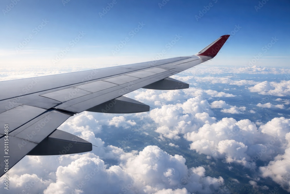 Obraz premium Airplane wing in flight with serene white clouds spread below