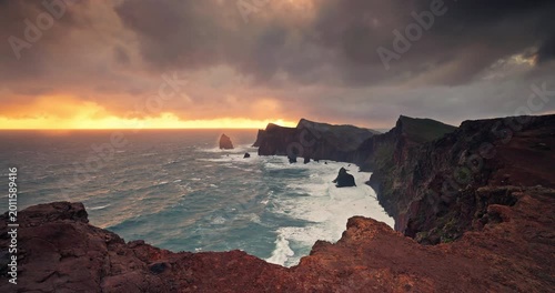 Dramatic golden sunset view of the volcanic rocky cliffs of Madeira island Portugal and stormy ocean at Ponta de Sao Lourenco coast