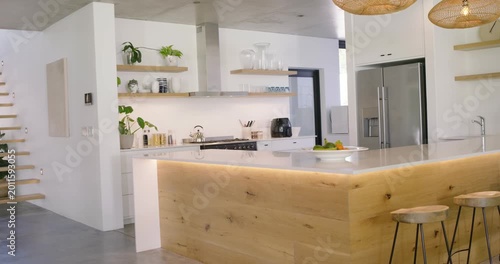Camera is dollying left-to-right to show wooden island with LED lighting, centering fruit bowl