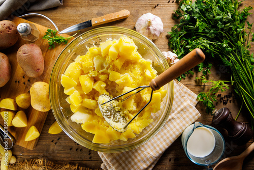 Foto making homemade mashed potatoes with a masher in a glass bowl