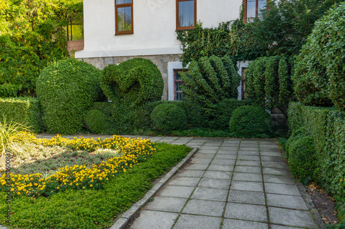 Foto Well-manicured garden with a stone path leading to white house