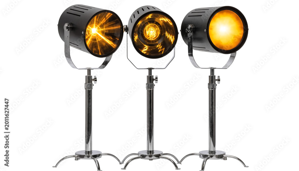 Obraz premium Three studio spotlights on stands illuminating bright yellow light against white background