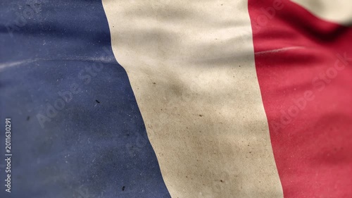 A France flag, made of old cloth, dirty and stained, flutters in the wind. A Worn France Flag Waves In The Breeze.