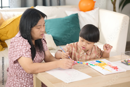A mother and child spending quality time together, engaged in a creative drawing activity. The mother is attentively assisting her child as they draw on paper with colorful markers