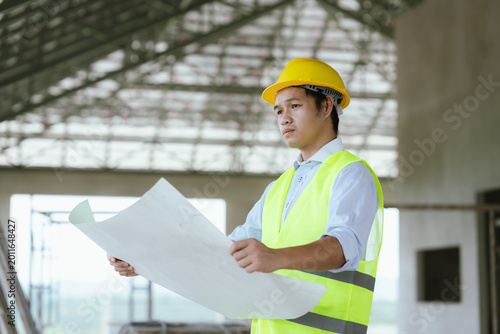 Obraz na płótnie Engineer in safety gear reviewing blueprints at a construction site, representing architecture, project planning, site inspection, and modern construction management