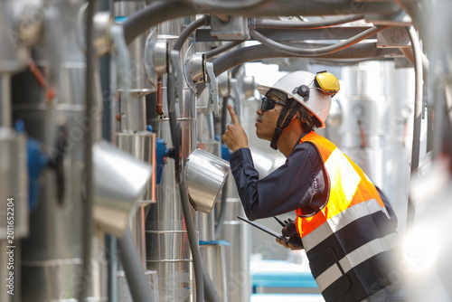 Technician working on industrial rooftop hvac equipment. He inspects complex cooling air piping network inside large plant room to ensure efficient operation