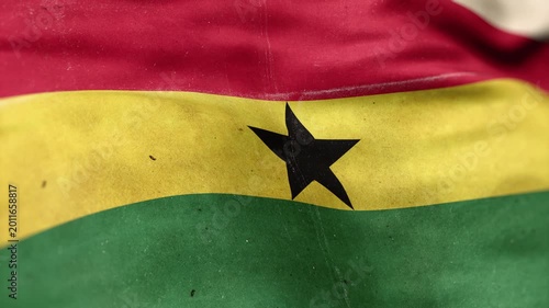 A Ghana flag, made of old cloth, dirty and stained, flutters in the wind. A Worn Ghana Flag Waves In The Breeze.