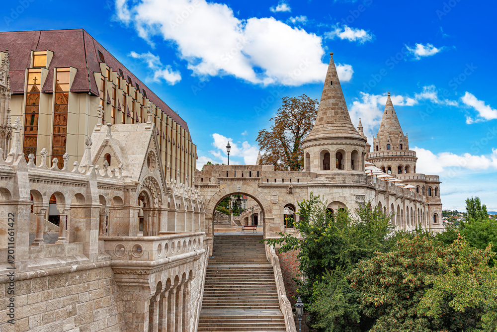 Naklejka premium The Fisherman's Bastion in Budapest features ornate stone towers and arched terraces under a bright blue sky.