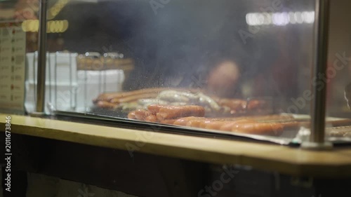 Bavarian Christmas market food stall, freshly grilled sausages steaming behind glass counter. Fast street food, warm winter snacks, traditional German flavors attract visitors in festive atmosphere
