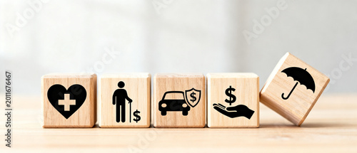 Wooden blocks with insurance symbols for health, old age, auto, financial protection, and umbrella of safety