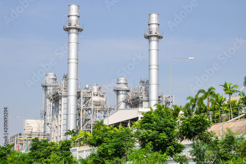 Fotografi Modern power plant with chimney smokestacks and green environment against blue sky