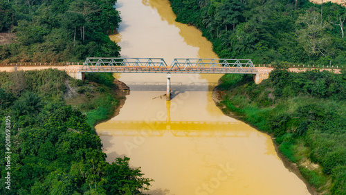 Canvastavla Illegal galamsey gold mining in ghana, polluted brown river passing under a brid