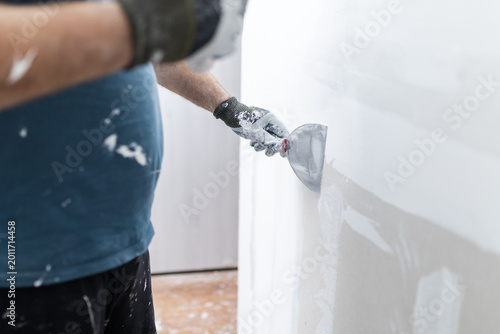Obraz na plátne Worker Smoothing Putty on White Interior Wall