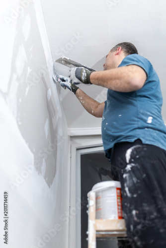 Worker Smoothing Fresh Plaster on Wall Near Window