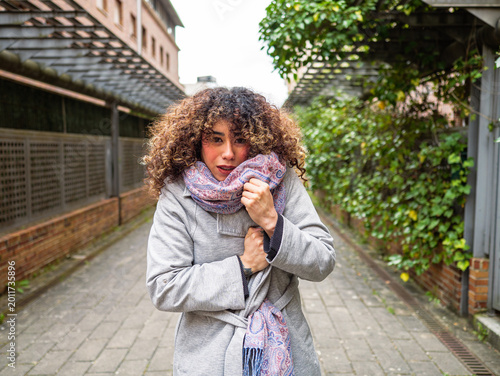 Bild auf Leinwand Female adjusting winter clothing with freezing expression ans shiver