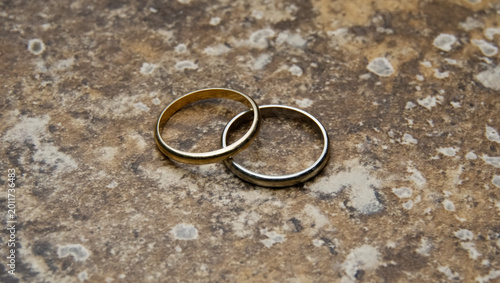 Two wedding rings together on a textured backdrop
