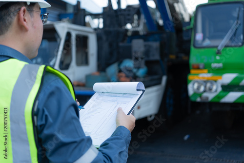 Bild auf Leinwand Engineer holding a checklist during crane inspection inside a maintenance bay, s
