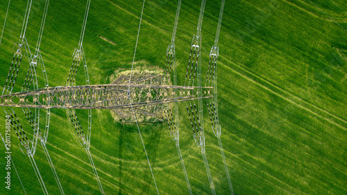 Fotografie Aerial top-down view of a high-voltage power line pylon in a vibrant green agricultural field