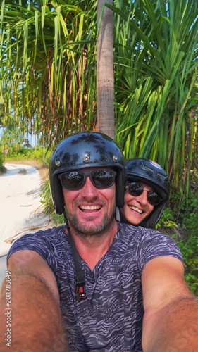 Zanzibar, Tanzania - 2025: Happy couple takes a selfie video while riding a scooter through a tropical palm grove. High-energy shot capturing authentic joy, freedom, and vacation fun in Zanzibar