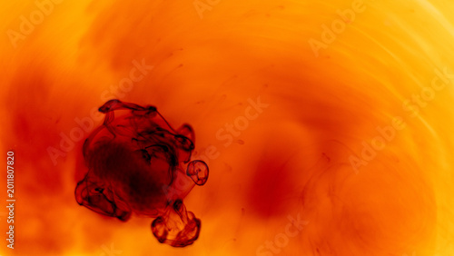 Obraz na płótnie Abstract red ink dissolving in warm yellow liquid background with soft flowing o
