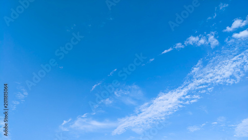 Clear blue sky with scattered white clouds on bright day.