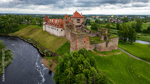 Aerial view of a Bauska castle surrounded by trees and a river