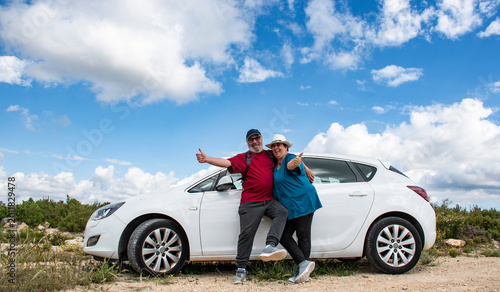 Canvastavla Pareja de jubilados al lado de su coche en la montaña un día soleado con nubes