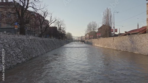 Sarajevo Miljacka river aerial drone rise revealing city skyline at sunset