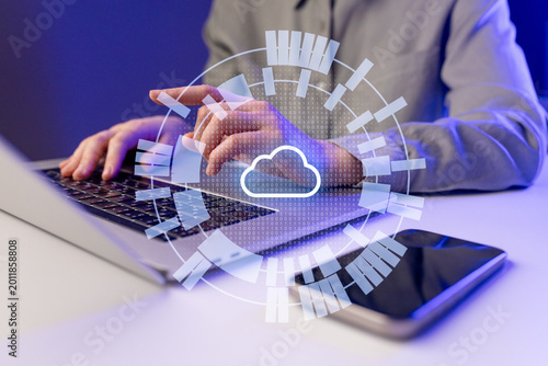 Person works on laptop with cloud data graphic during nighttime in a home setting