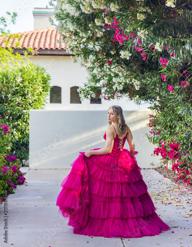 teen girl walking in a garden, showing off the back detail of a beautiful pink party dress